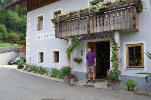 un hombre parado fuera de un edificio blanco con flores en Turnerhof, en Millstatt