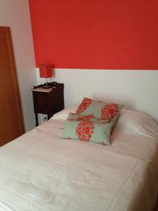 a bed with two pillows on it with a red wall at Terraço da Vila in Ponte de Lima