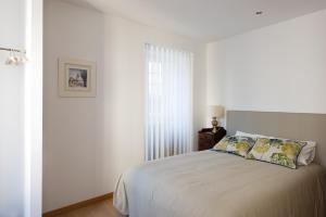 a white bedroom with a bed and a window at Terraço da Vila in Ponte de Lima