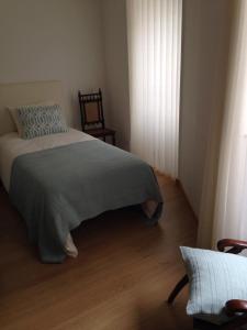 a bedroom with a bed and a chair and a window at Terraço da Vila in Ponte de Lima