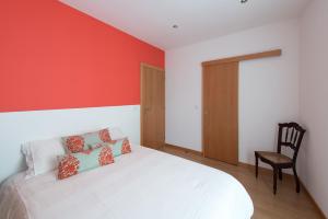 a bedroom with a white bed and a chair at Terraço da Vila in Ponte de Lima