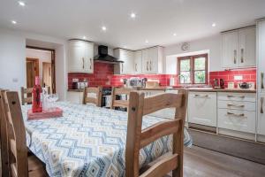 a kitchen with a table and a kitchen with white cabinets at The Stables - 3 Bedroom Cottage - Beavers Hill in Manorbier