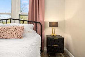 a bed with a lamp on a nightstand next to a window at Tranquil 3 Bed Retreat Sleeps 7 in Peoria +37 photos