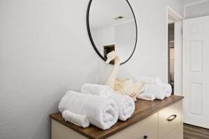 a bathroom with towels on a dresser with a mirror at The Modern Elm Escape a cozy 2bd in the Heights in Peoria Heights +44 photos