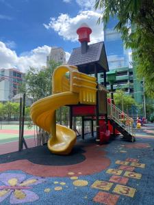 ein Spielplatz mit einer gelben Rutsche in einem Park in der Unterkunft Resort Living 2BR - Ultra Fast Wifii - BTS Chong Nonsi in Bangkok