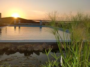 a swimming pool with a sunset in the background at Horta da Quinta in Mértola