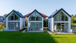 a group of houses with chairs on a lawn at Jesionowa 3 Domki in Rowy