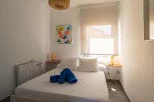 a bedroom with a white bed with a blue object on it at Ático céntrico con vistas a Los Molinos in Campo de Criptana