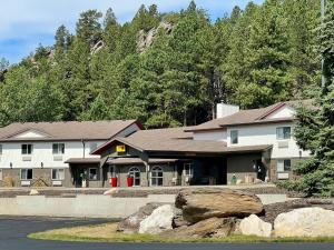 a building in front of a mountain with trees at Super 8 by Wyndham Custer/Crazy Horse Area in Custer