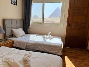 开罗Tamara Front Pyramids & Valley Temple View的酒店客房设有两张床和一个带金字塔的窗户。