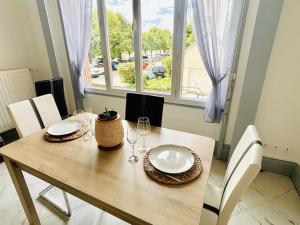 a dining room table with plates and wine glasses at Le Magaline in Sainte-Savine