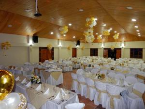 un salón de banquetes con mesas blancas, sillas y globos en Hotel La Libertad, en Paipa