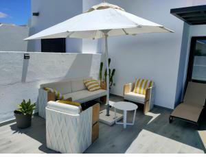 a patio with a couch and an umbrella and chairs at Goikiri in Playa Blanca