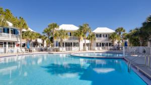 Una gran piscina con palmeras y edificios. en The Bungalows at Seagrove 114, en Seagrove Beach