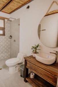 Un baño con lavabo, inodoro y espejo. en Pietra Hotel, en Sáchica