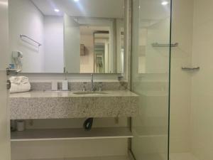 a bathroom with a sink and a glass shower at Flat 205 completo no Granja Brasil em Itaipava in Petrópolis