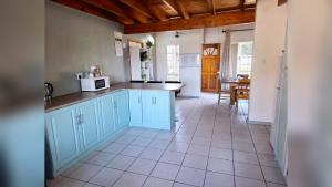a kitchen with blue cabinets and a table with a microwave at Mond Kleine Guest House in Kleinmond