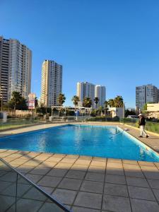 a man walking by a swimming pool in a city at Depto Marina Costa a pasos de ENJOY in Coquimbo