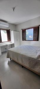 a bedroom with a large bed and two windows at Bangalô 12 na praia de Guaratiba, Prado, ba in Prado