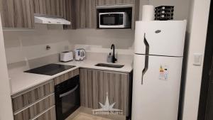 una cocina con nevera y microondas en Departamento 318 en complejo premiun de Pinamar Norte, en Pinamar