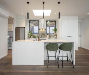 a kitchen with a white island with two bar stools at Crystal Waters in Queenstown