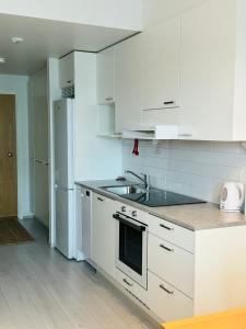 Una cocina blanca con fregadero y refrigerador. en Lux home III, en Tampere
