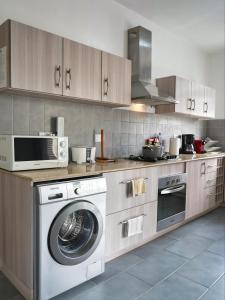 a kitchen with a washing machine and a microwave at Villa Alexis - Location de vacances à Trou aux Biches in Trou aux Biches