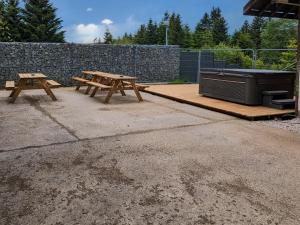 2 Picknicktische und ein Grill auf einer Terrasse in der Unterkunft Chalet familial avec salle de jeux et spa, près de Gérardmer, pour 15 pers. - FR-1-589-647 in Ban-sur-Meurthe-Clefcy