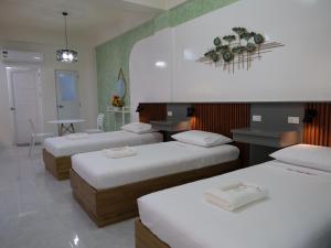 a room with three beds in it with a table and a table at Karas Pension House East in Tuguegarao City