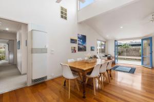 Un comedor con una mesa de madera y sillas blancas. en Lonsdale Back Beach Retreat, en Point Lonsdale