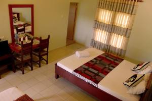 a room with two beds and a table and a table at Green Land Guest House in Pinnawala