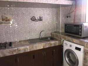 a kitchen with a washing machine and a microwave at Maison Samy in Ifrane