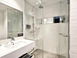 a white bathroom with a sink and a shower at GLAD Gangnam COEX Center in Seoul