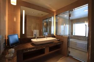 a bathroom with a sink and a television on a counter at Hotel Monterey Grasmere Osaka in Osaka