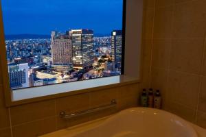 a bath tub in a bathroom with a window at Hotel Monterey Grasmere Osaka in Osaka