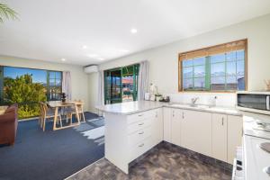 a kitchen with white cabinets and a dining room with a table at Great Location, Affordable, Units in Kaikoura