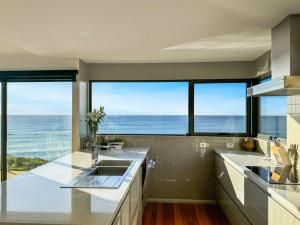 a kitchen with a view of the ocean at Ava - Luxe Oceanfront Beach House in Falmouth