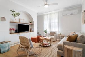 a living room with a couch and a tv at Maggies The Little Black Cottage - Hunter Valley in Cessnock