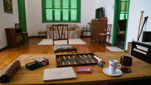 a living room with a wooden table and a room with green doors at Casa Charmosa em Santa Teresa lugar tranquilo e cultural in Rio de Janeiro
