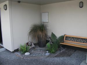 a bench sitting next to a wall with plants at Scenicland Motels in Greymouth