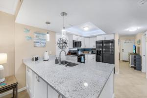 eine Küche mit weißen Schränken und einer Granitarbeitsplatte in der Unterkunft Waterfront Island Oasis! Heated Pool with Stunning View & 2 Full Bath in Marco Island