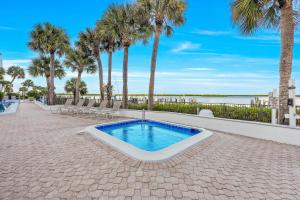 einen Pool mit Palmen und Strand in der Unterkunft Waterfront Island Oasis! Heated Pool with Stunning View & 2 Full Bath in Marco Island
