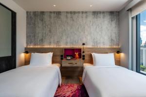 two beds in a room with two windows at Moxy Bangkok Ratchaprasong in Bangkok