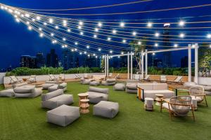 a rooftop patio with chairs and tables and lights at Moxy Bangkok Ratchaprasong in Bangkok