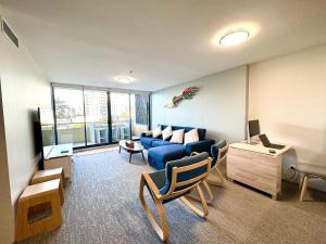 a living room with a blue couch and a table at Ocean View Private Cronulla Apartment in Cronulla