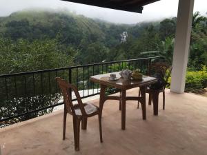 a table and chairs on a balcony with a view of a mountain at Chamodya Home Stay in Ella
