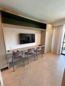 a room with a table with chairs and a tv on the wall at Eco Resort Praia Dos Carneiros - Vizinho a Igrejinha in Praia dos Carneiros