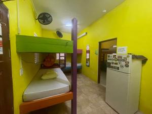 a small room with a bunk bed and a refrigerator at Travellers Palm Backpackers in Caye Caulker