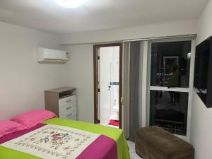 瓜拉派瑞Centro de Guarapari 3 quartos, dois com Ar的一间卧室配有一张带绿色和粉色毯子的床
