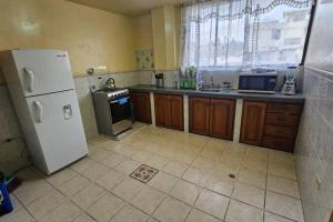 a kitchen with a white refrigerator and a window at Lindo Departamento a estrenar in Latacunga